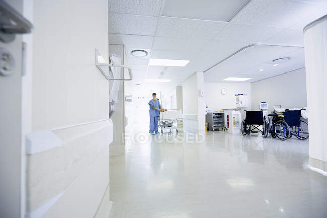 Médicos empujando cama de hospital a lo largo del pasillo - foto de stock
