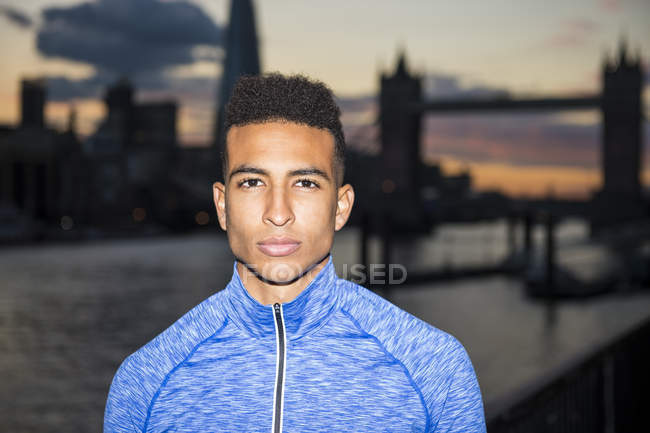 Young man, Tower Bridge in background, Wapping, London, UK — Stock Photo