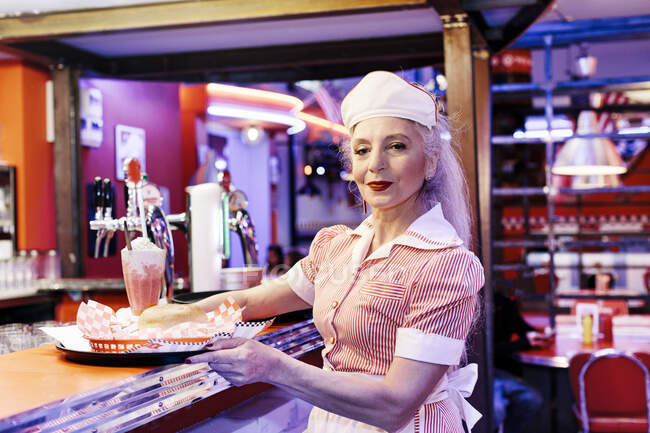 Portrait of mature female waitress in 1950's diner — Stock Photo