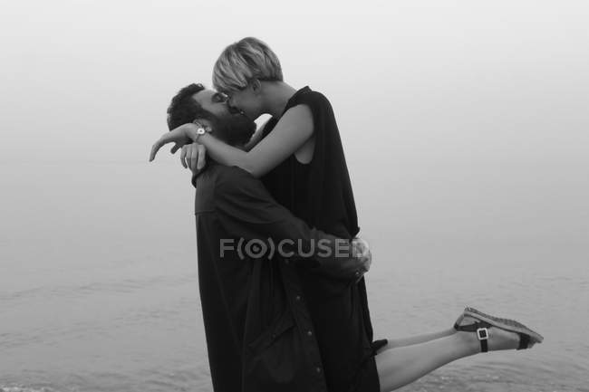 Jovem casal na praia, abraçando e beijando — Fotografia de Stock
