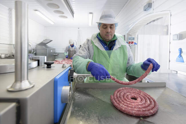 Worker making Italian sausages in sausage factory — Stock Photo