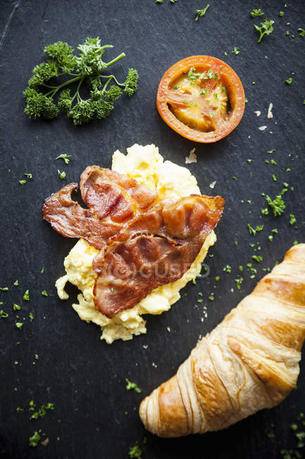 Still life of croissant with bacon, omelette and tomato slice — Stock Photo