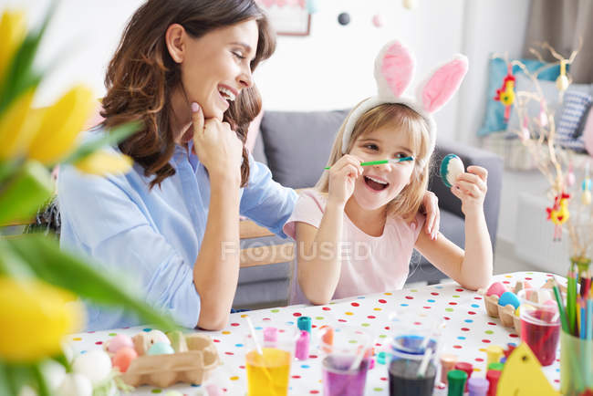 Woman and daughter painting Easter eggs at table — Stock Photo