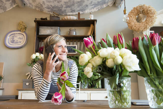 Florista em loja de flores, usando smartphone — Fotografia de Stock