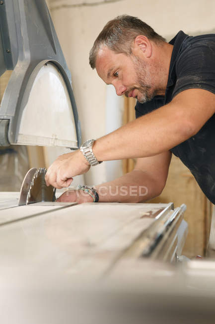 Man inspecting bench saw in workshop — Stock Photo