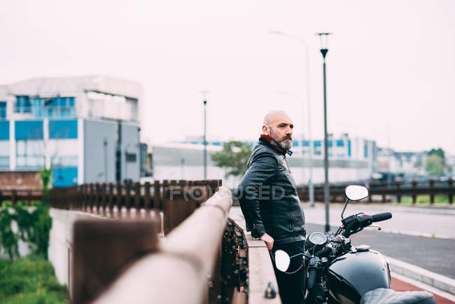 Зрелый мотоциклист наблюдает со стороны дороги — стоковое фото