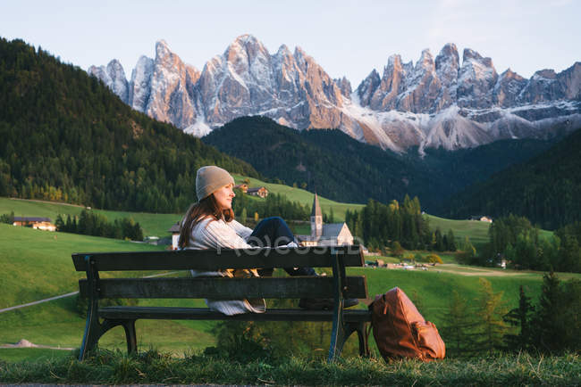 Woman relaxing on park bench, Santa Maddalena, Dolomite Alps, Val di Funes (Funes Valley), South Tyrol, Itália — Fotografia de Stock