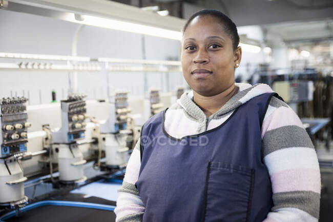 Portrait of female factory worker in front of programmed embroidery machines in clothing factory — Stock Photo