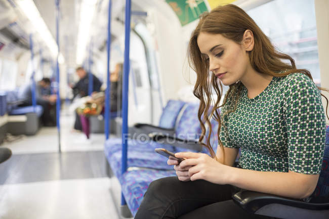 Frau im Zug schaut aufs Smartphone — Stockfoto