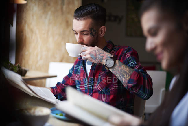Пара п'є каву читаючи газети — стокове фото