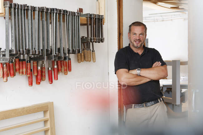 Retrato del hombre en taller con herramientas manuales - foto de stock