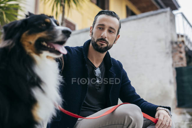 Середній дорослий чоловік сидить з собакою на міській сходинці — стокове фото