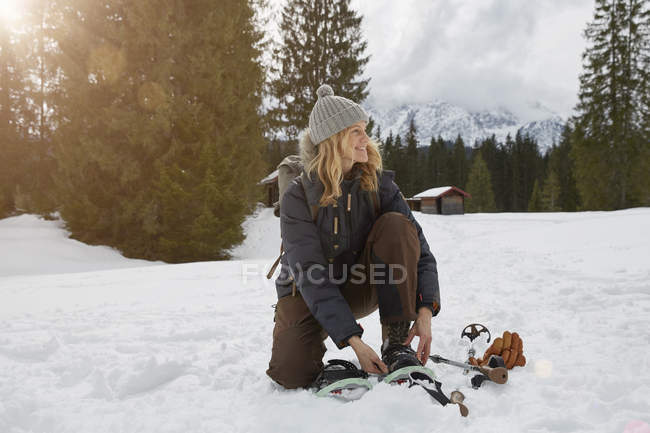 Mature woman putting on snow shoes in snowy landscape, Elmau, Bavaria, Germany — Stock Photo