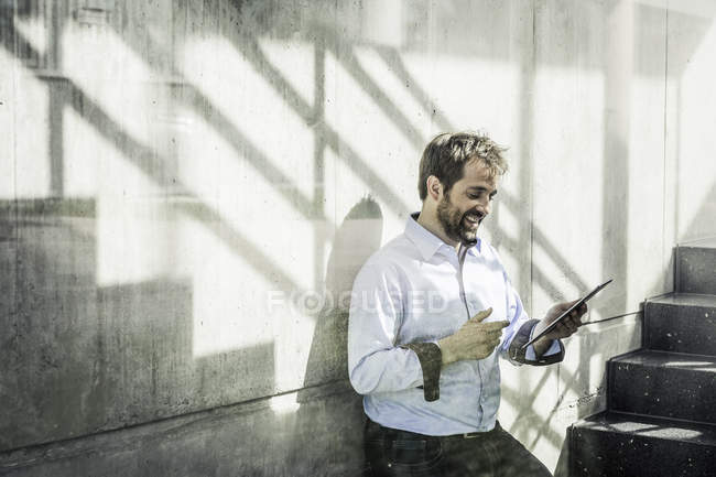 Бізнесмен в офісних сходах дивиться на цифровий планшет — стокове фото