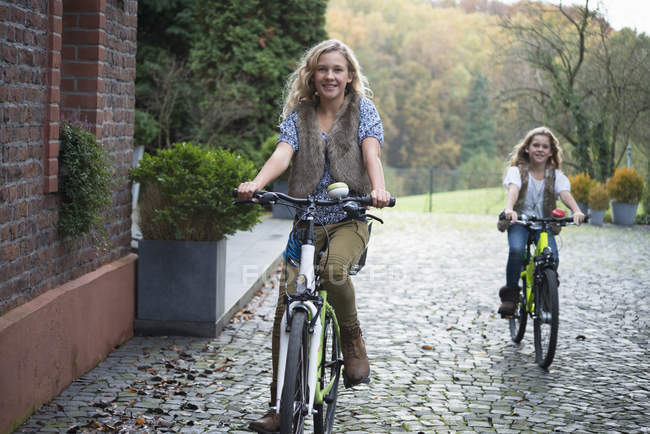 Dos hermanas en bicicleta juntas en el parque - foto de stock