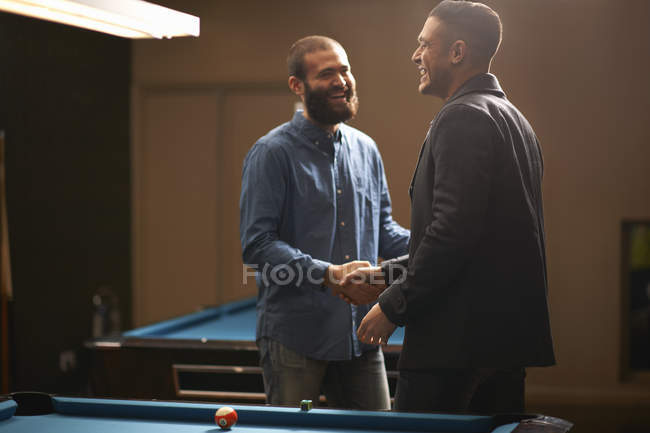 Men shaking hands at pool table — Stock Photo