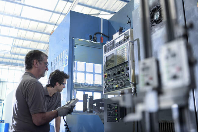 Engineer and apprentice operating lathe in precision casting factory — Stock Photo