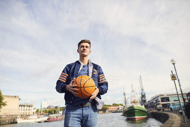 Young man near river, holding basketball, Bristol, UK — Stock Photo