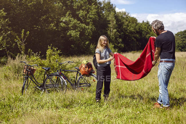 Coppie preparazione coperta picnic in campo rurale — Foto stock
