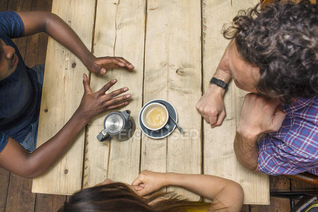 Вид сверху на друзей, разговаривающих за столиком в кафе — стоковое фото