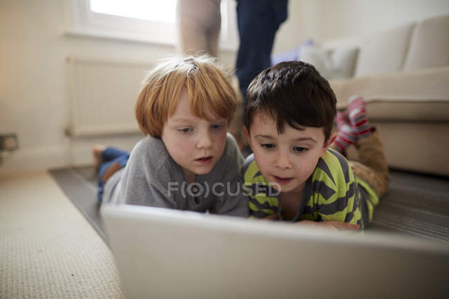 Brothers playing laptop game on room rug — Stock Photo