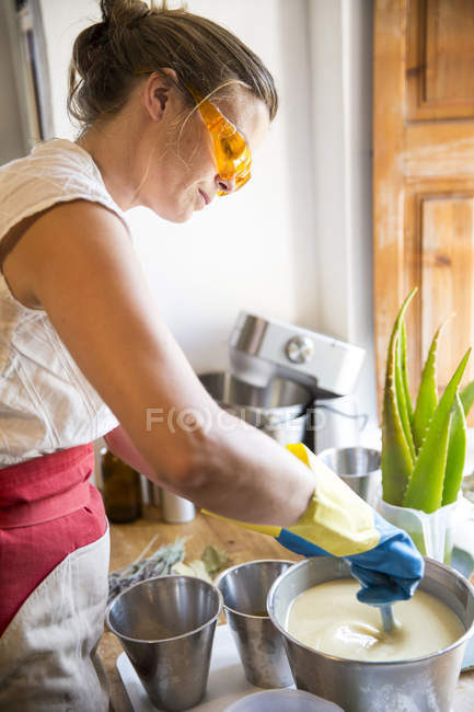 Seção média da mulher mexendo tigela de sabão líquido de lavanda na oficina de sabão artesanal — Fotografia de Stock