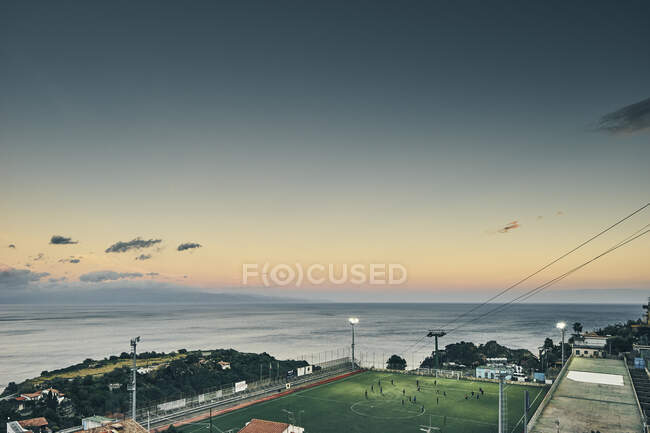 Campo de deportes de fútbol iluminado en la costa, Taormina, Sicilia, Italia - foto de stock