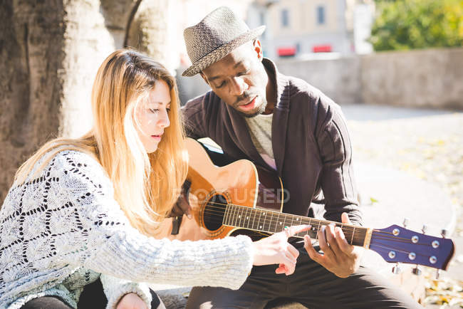 Пара учится играть на гитаре в парке — стоковое фото