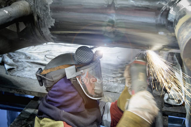 Worker grinding pipe in gas-fired power station — Stock Photo