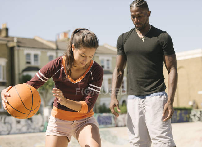Mujer y joven practicando baloncesto en skatepark - foto de stock