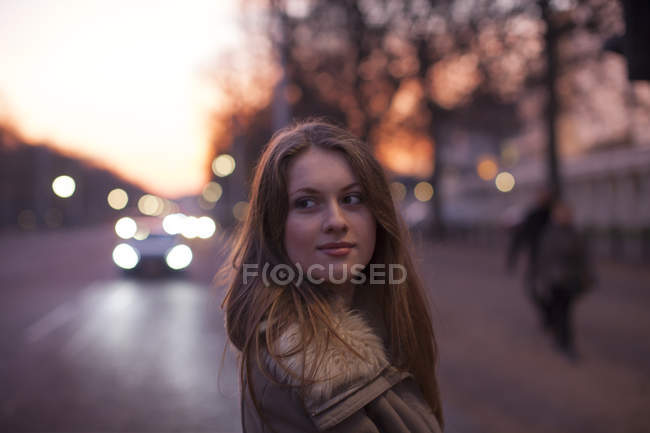 Mujer joven en la calle, tráfico en segundo plano, Londres, Reino Unido - foto de stock