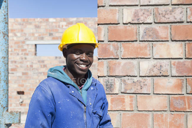Porträt des Bauunternehmers mit hartem Hut, der lächelnd in die Kamera blickt — Stockfoto