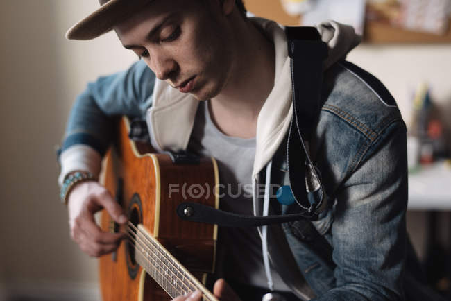 Молодий чоловік вдома, грає на гітарі — стокове фото