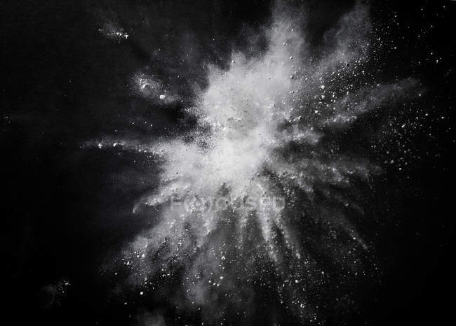 Білий пил вибухає середнє повітря на чорному тлі — стокове фото