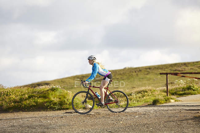 Vista lateral do ciclista andando na estrada de cascalho — Fotografia de Stock