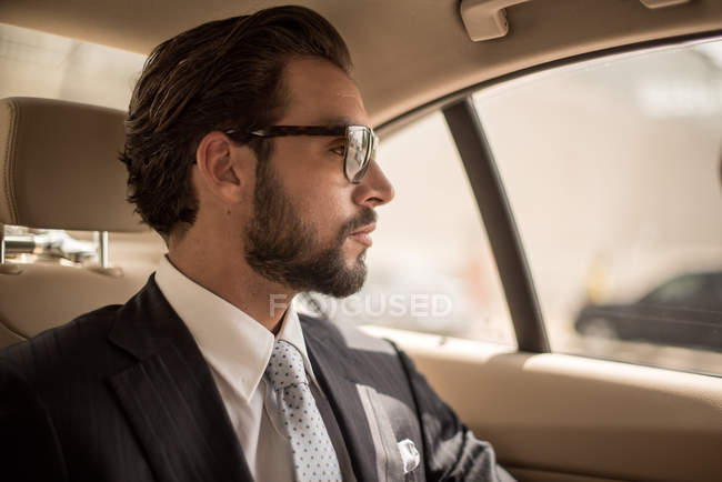 Молодой бизнесмен, выглядывающий с заднего сиденья автомобиля, Дубай, Объединенные Арабские Эмираты — стоковое фото