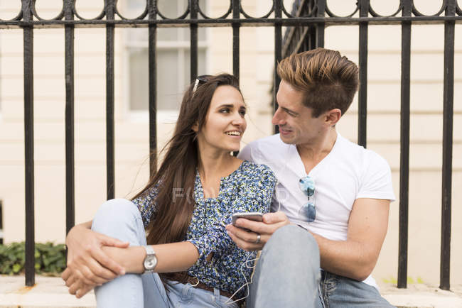 Junges Paar sitzt auf dem Bürgersteig, London, Großbritannien — Stockfoto