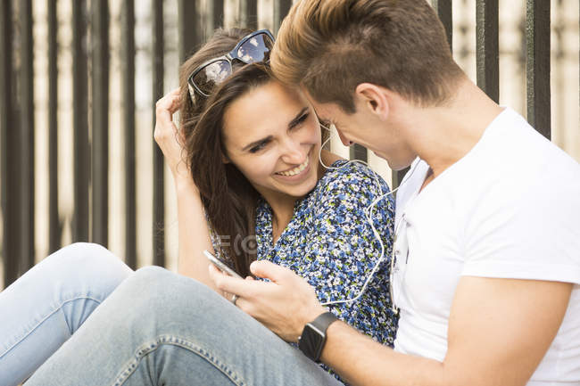 Glückliches junges Paar sitzt auf dem Bürgersteig, London, Großbritannien — Stockfoto