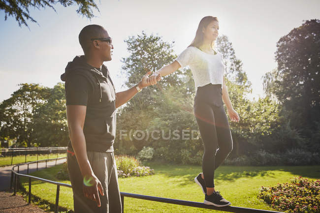 Femme tenant la main avec entraîneur personnel marchant sur la clôture du parc — Photo de stock