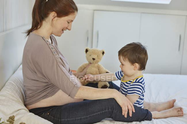Side view of baby boy touching pregnant mothers stomach — Stock Photo