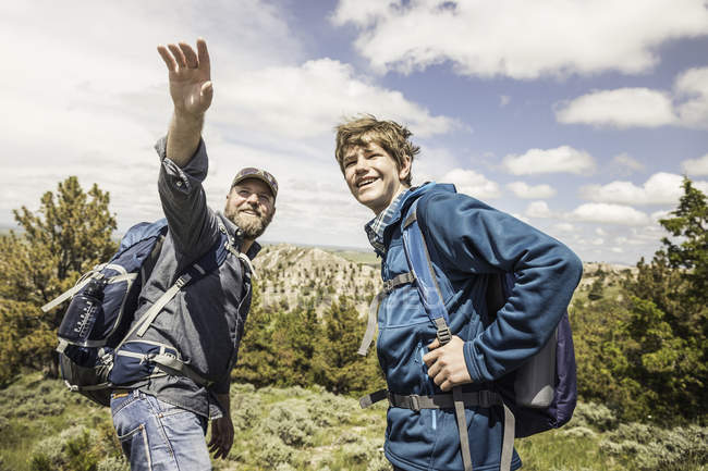Father and teenage son pointing out to landscape on hiking trip, Cody, Wyoming, USA — Stock Photo
