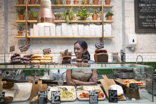 Waitress standing behind cafe display cabinet — Stock Photo