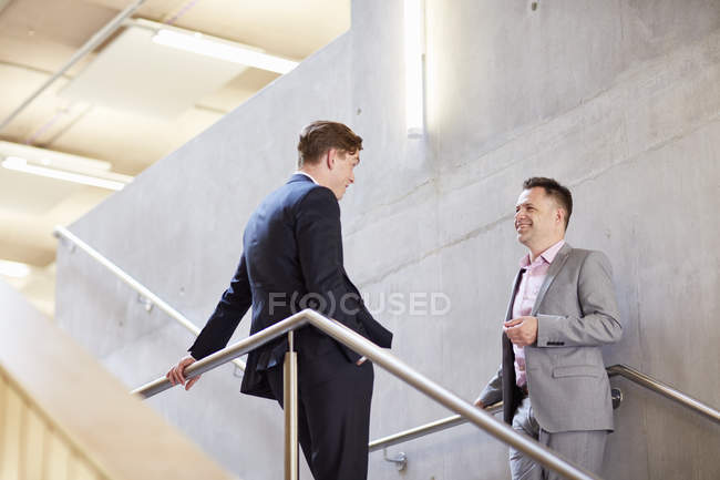 Двое бизнесменов общаются на служебной лестнице — стоковое фото