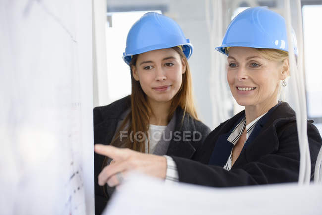 Businesswoman pointing at blue print in new office building — Stock Photo