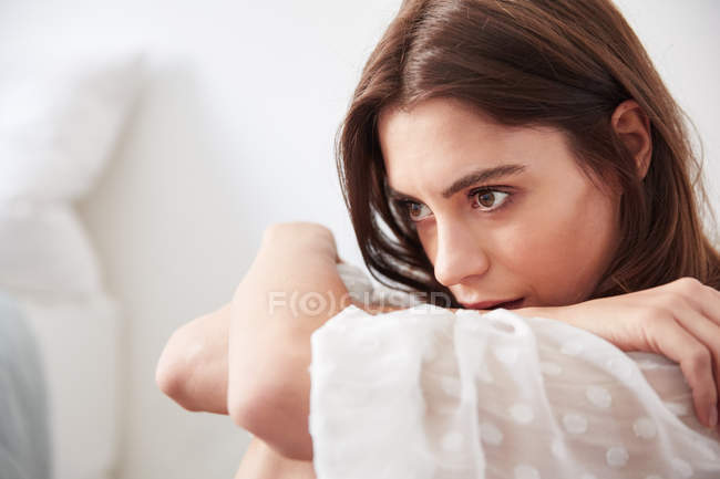 Young woman sitting on floor near bed — Stock Photo