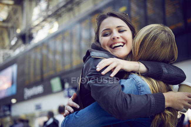 Women hugging in train station concourse, London, UK — Stock Photo