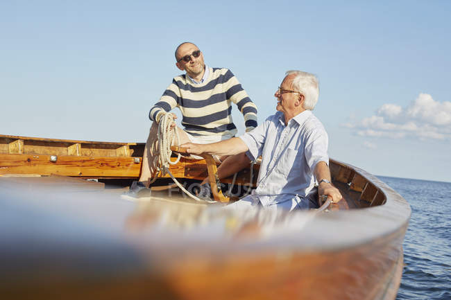 Друзья сидят в лодке в голубом океане — стоковое фото