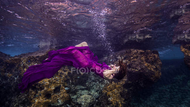 Donna inarcata all'indietro, drappeggiata in tessuto viola puro, vista subacquea — Foto stock