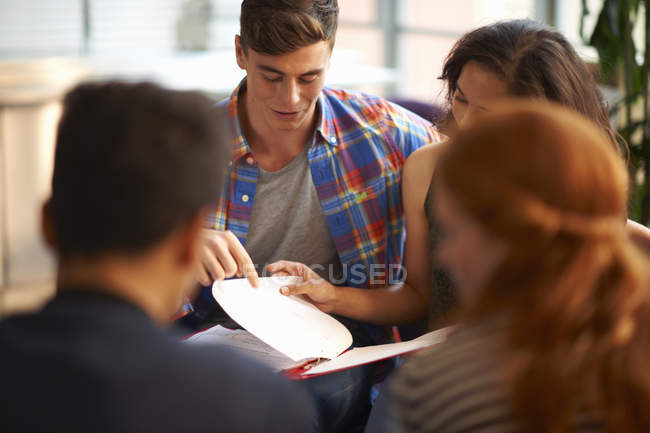 Over the shoulder view of young female and male college students reading file in common room — Stock Photo