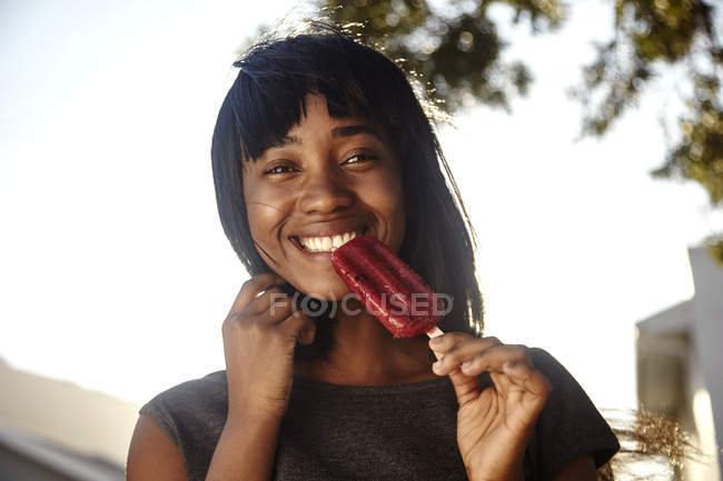 Портрет молодой женщины, на открытом воздухе, едят ледяной лед — стоковое фото